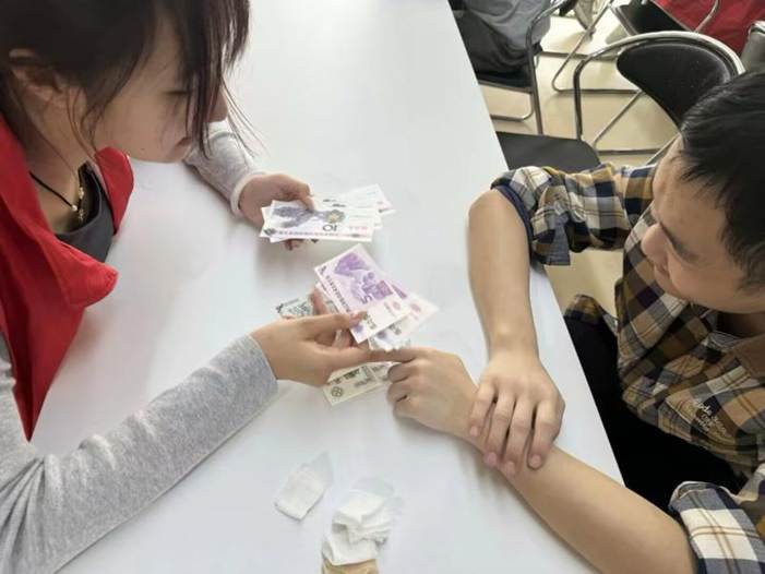 图2 志愿者引导学员认识货币