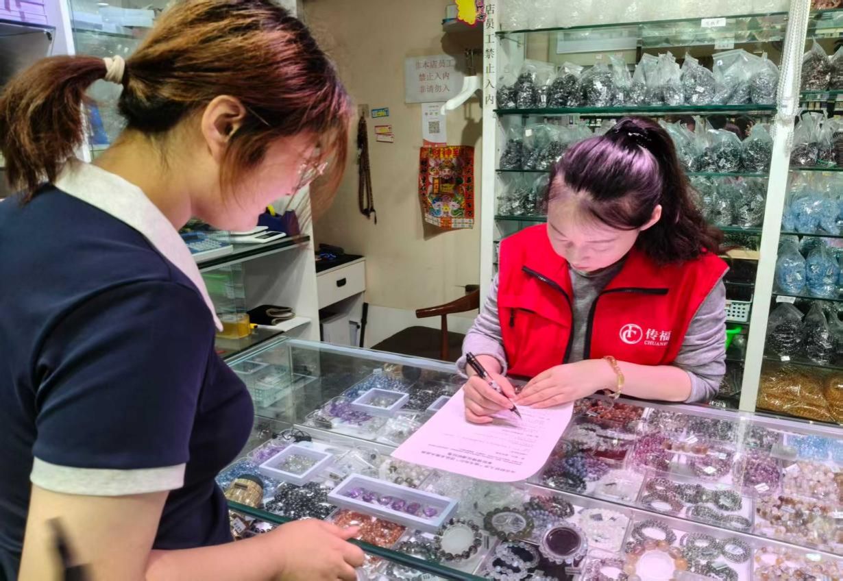 图为团队成员向水晶商户发放调研问卷，商户填写调研资料。尹非=菲然供图_new